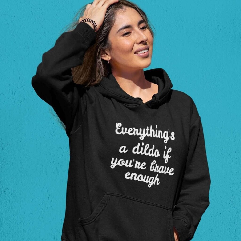 Woman wearing black hooded sweatshirt with the text 'Everything's a dildo if you're brave enough' printed on the front.