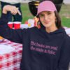 Woman wearing a navy blue hoodie sweatshirt with the text 'The boobs are real, the smile is fake.' printed in pink on the front.