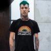Man wearing a black t-shirt with a graphic of a rainbow and the words 'Spread negativity' printed on the front.