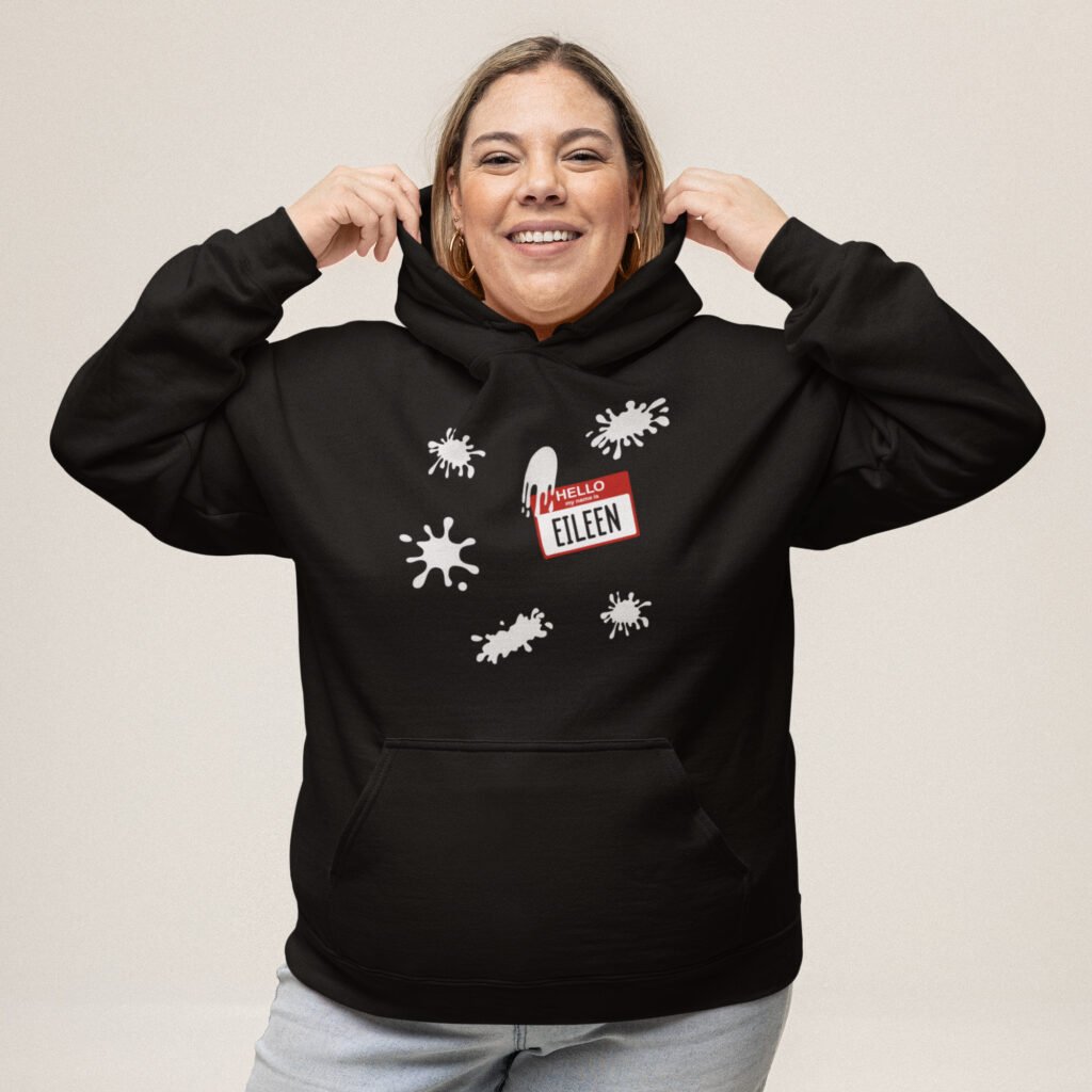 Woman wearing black hoodie sweatshirt with Eileen name tag and white splatters printed on the front.