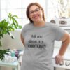 Smiling woman wearing a light grey t-shirt with the text 'Ask me about my lobotomy' printed on the front.