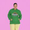 Woman wearing a green hoodie sweatshirt with an image of a rainbow and the words 'Thanks for the childhood trauma' printed on the front. The word Thanks is large and the rest of the words are smaller under.
