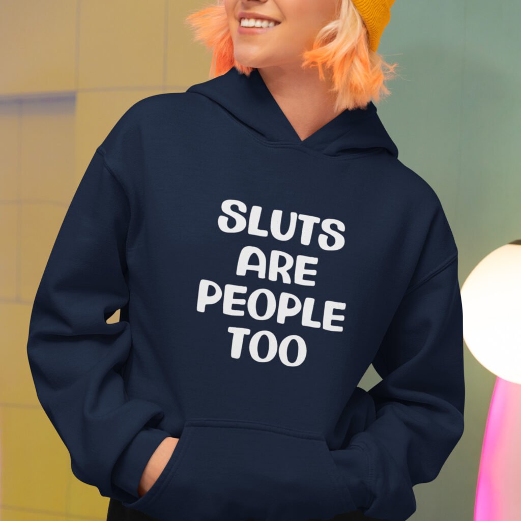 Woman wearing a navy blue hoodie sweatshirt with the text 'Sluts are people too' printed on the front.