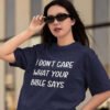 Woman wearing sunglasses and a navy blue t-shirt with the text 'I don't care what your bible says' printed on the front.
