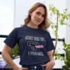 Woman wearing a navy blue t-shirt that has an image of a strap-on dildo and the words 'Just the tip. I promise.' printed on the front.