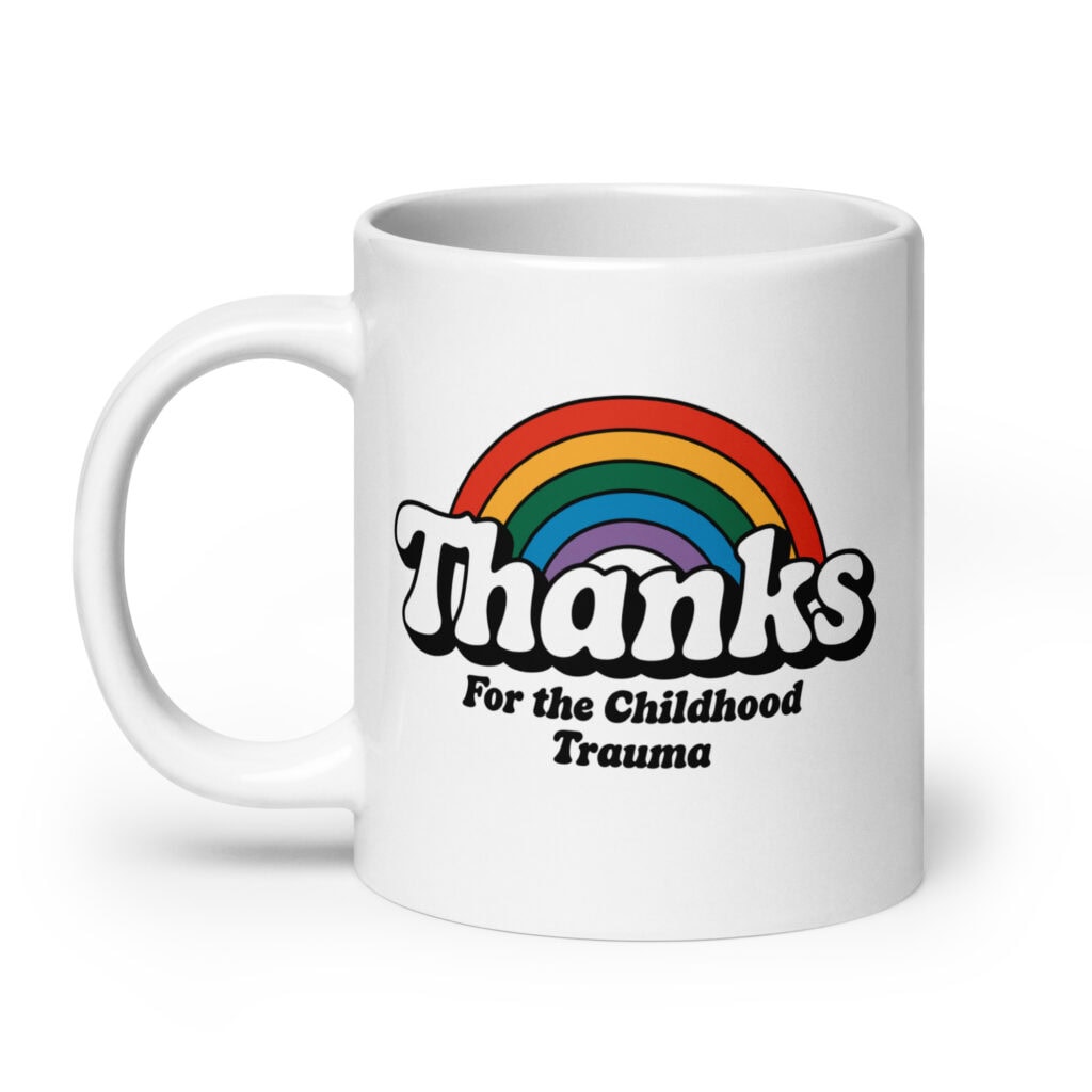 White ceramic mug with a rainbow and the text "Thanks for the childhood trauma' printed on both sides.