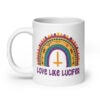 White ceramic mug with an image of a boho style rainbow. There is an upside down cross in the center arch of the rainbow and the text 'Love like Lucifer' printed under. The graphics are printed on both sides of the mug.