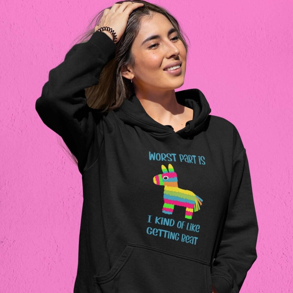 Woman wearing black hoodie sweatshirt with an image of a colorful donkey pinata with the words 'Worst part is I kind of like getting beat' printed on the front.
