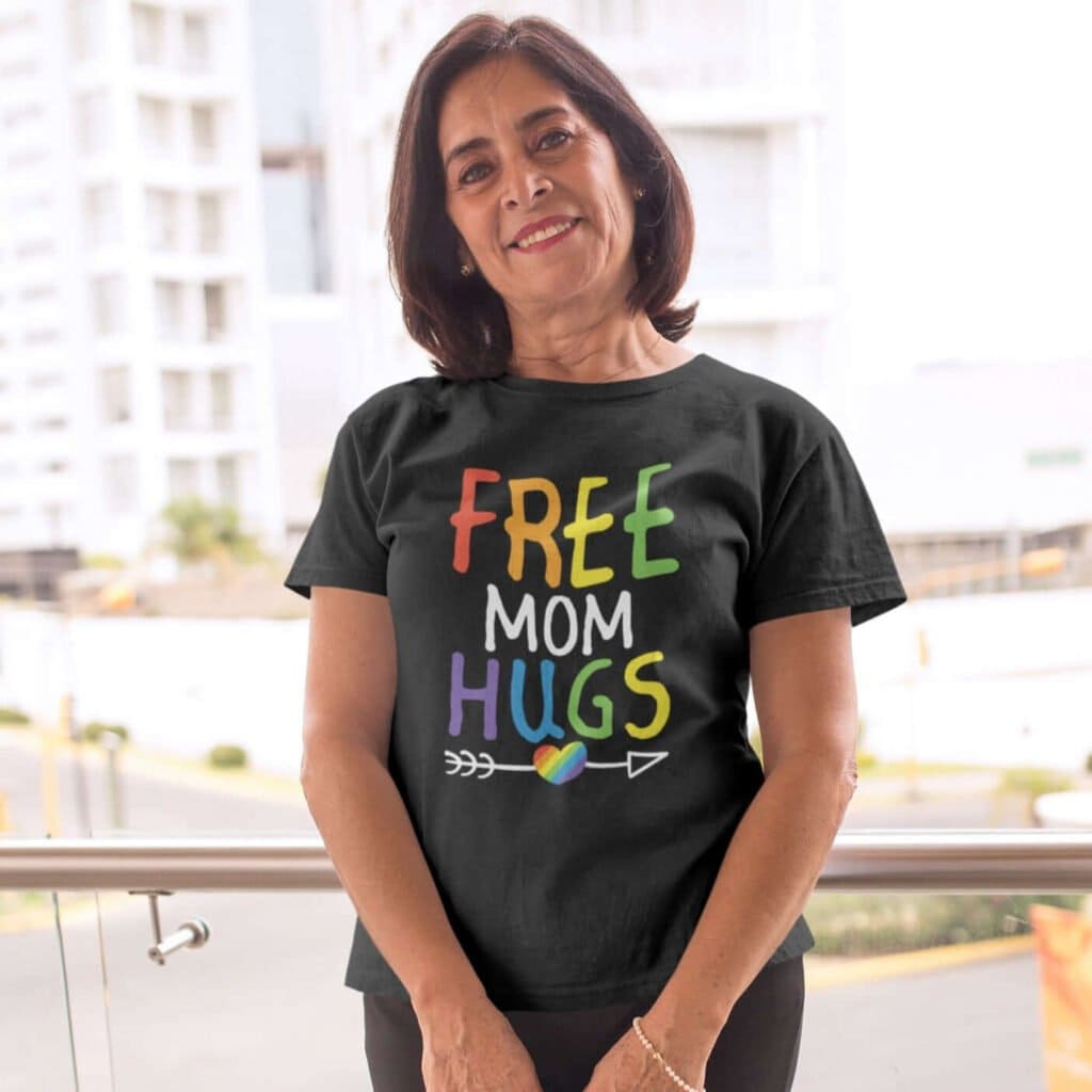 Older woman wearing black t-shirt with the text 'Free Mom hugs' in rainbow lettering printed on the front.