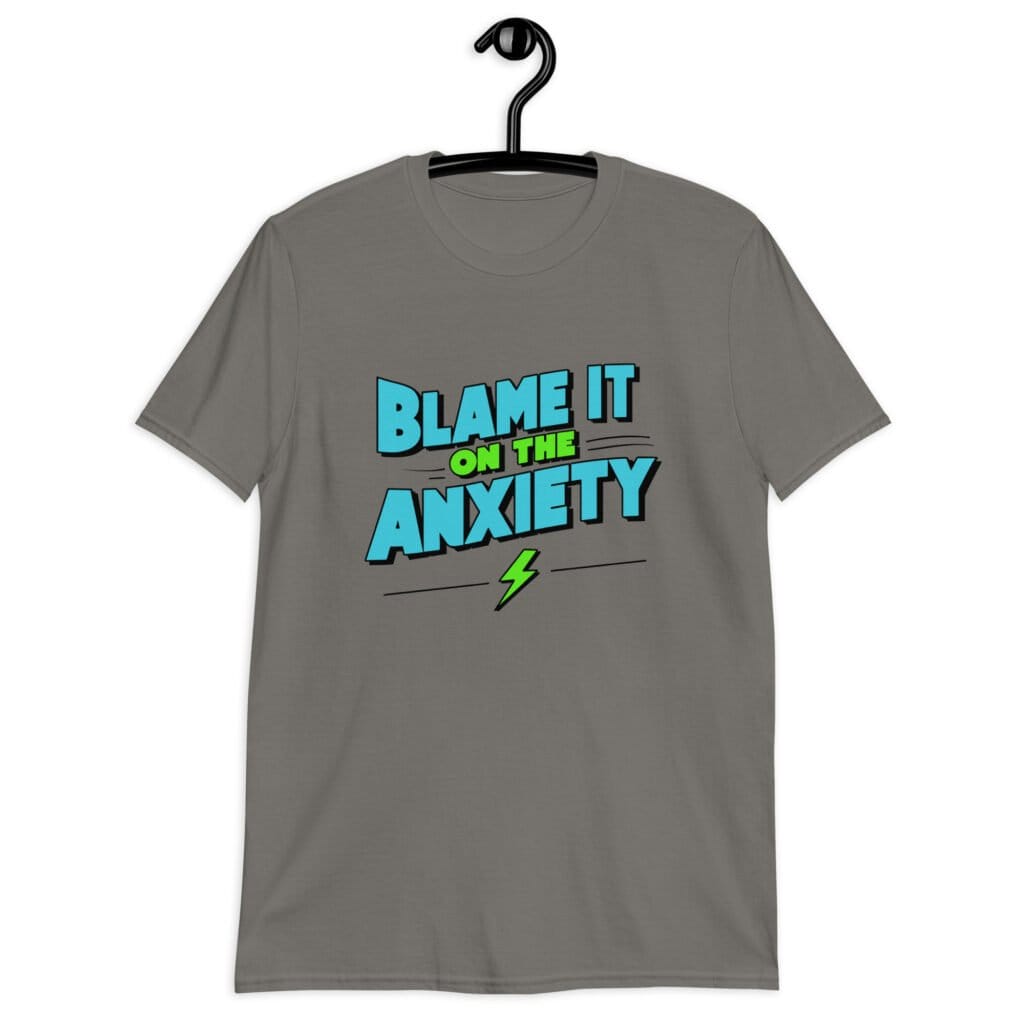 Charcoal grey t-shirt with the phrase 'Blame is on the anxiety' printed on the front. The graphics are bold and in aqua and lime green.