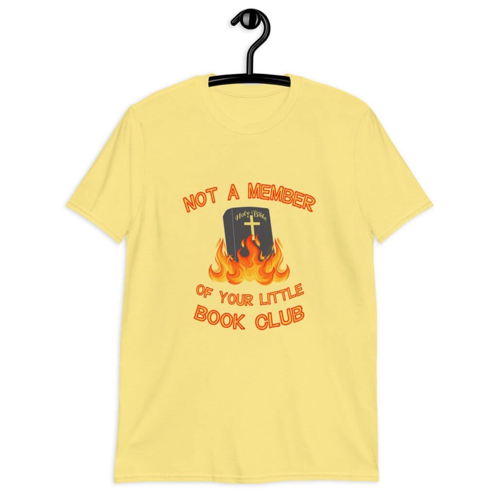 Cornsilk yellow t-shirt with image of a burning bible and the text 'Not a member of your little book club' printed on the front.