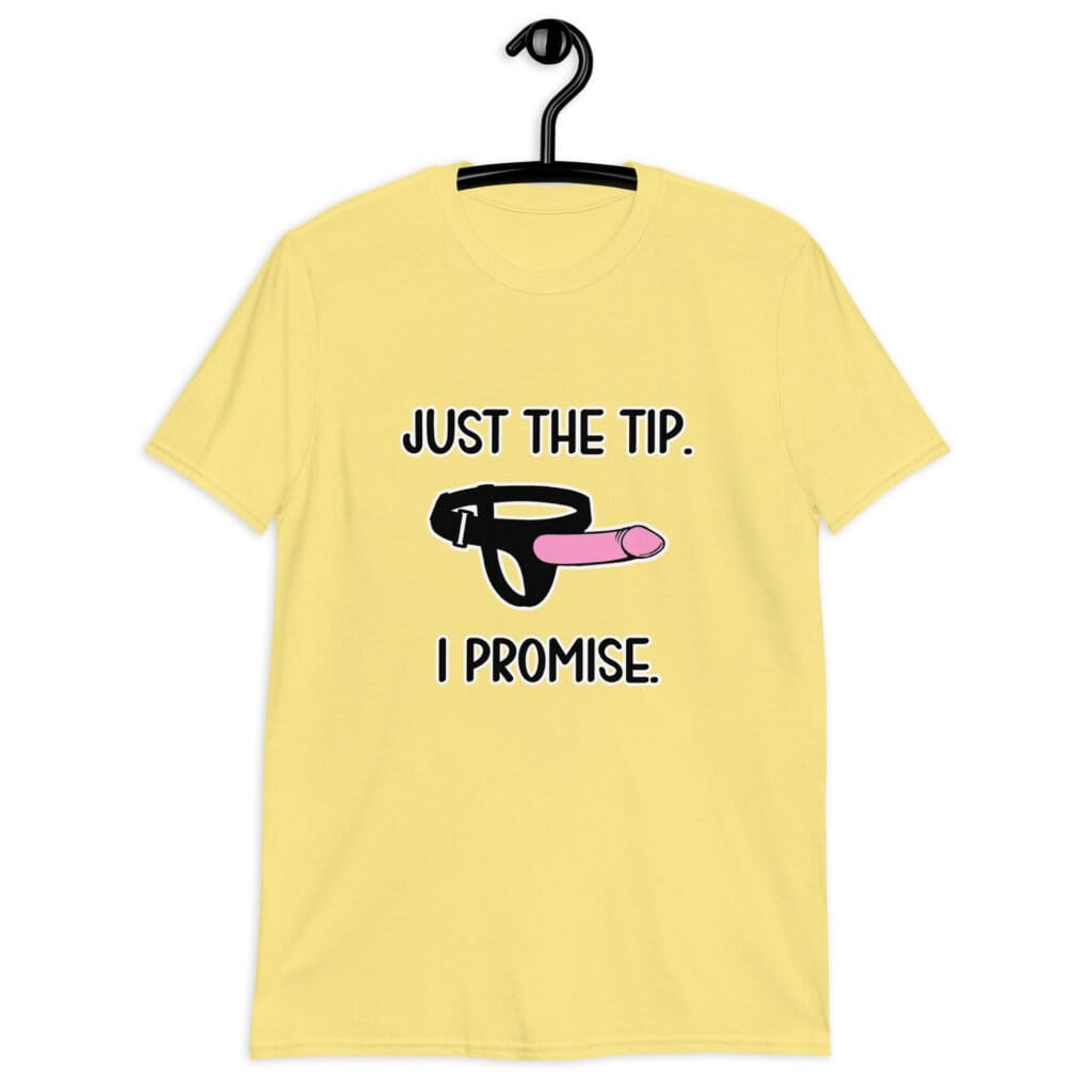 Cornsilk yellow t-shirt that has an image of a strap-on dildo and the words 'Just the tip. I promise.' printed on the front.