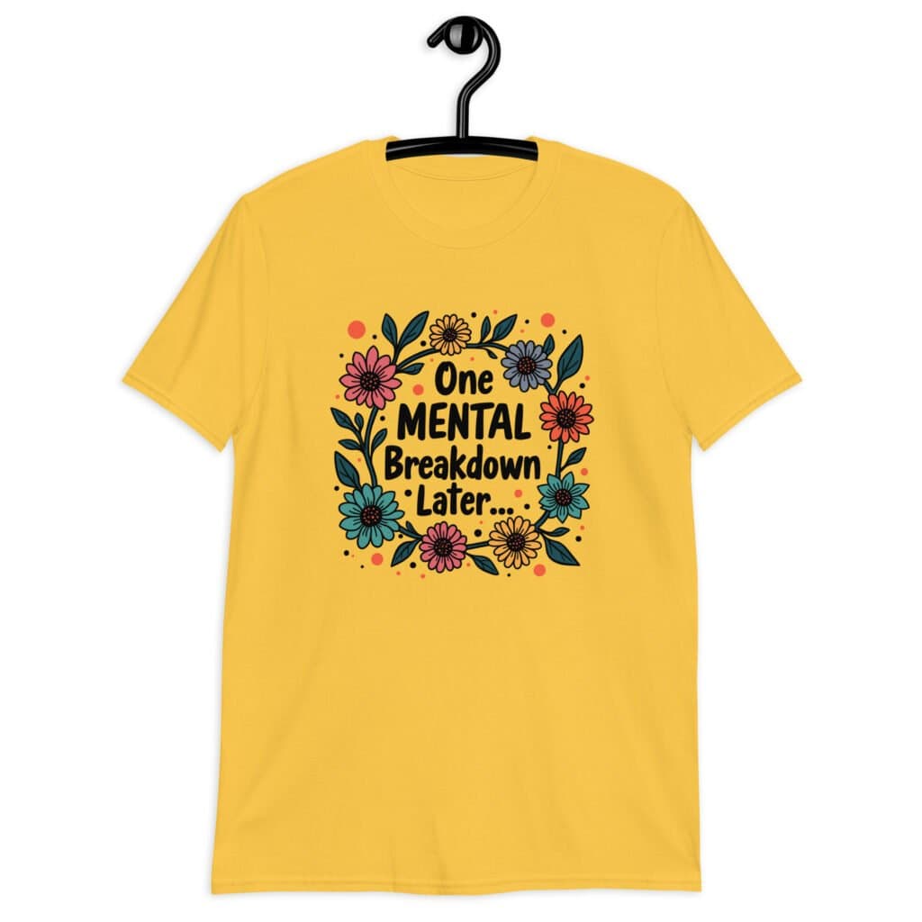 Daisy yellow t-shirt with a multi color floral wreath design printed on the front. The words 'One mental breakdown later...' are printed in the center of the wreath.