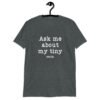Dark heather grey t-shirt with the text 'Ask me about my tiny penis' printed on the front. The word tiny is much smaller than the rest of the text.