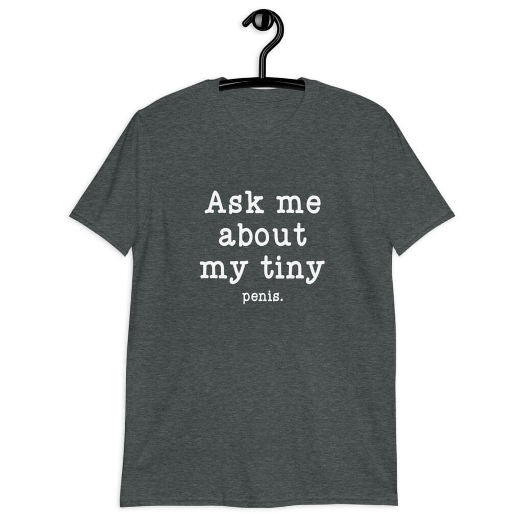 Dark heather grey t-shirt with the text 'Ask me about my tiny penis' printed on the front. The word tiny is much smaller than the rest of the text.