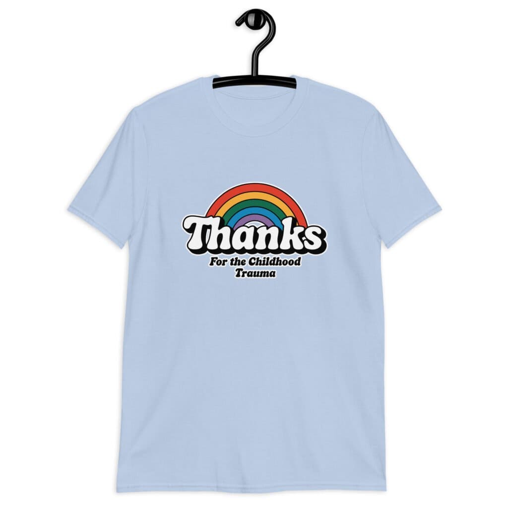 Light blue t-shirt with an image of a rainbow and the words 'Thanks for the childhood trauma' printed on the front. The word Thanks is large and the rest of the words are smaller under.