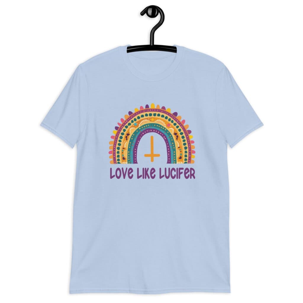 Light blue t-shirt with an image of a boho style rainbow. There is an upside down cross in the center arch of the rainbow and the text 'Love like Lucifer' printed under. The graphics are printed on the front.