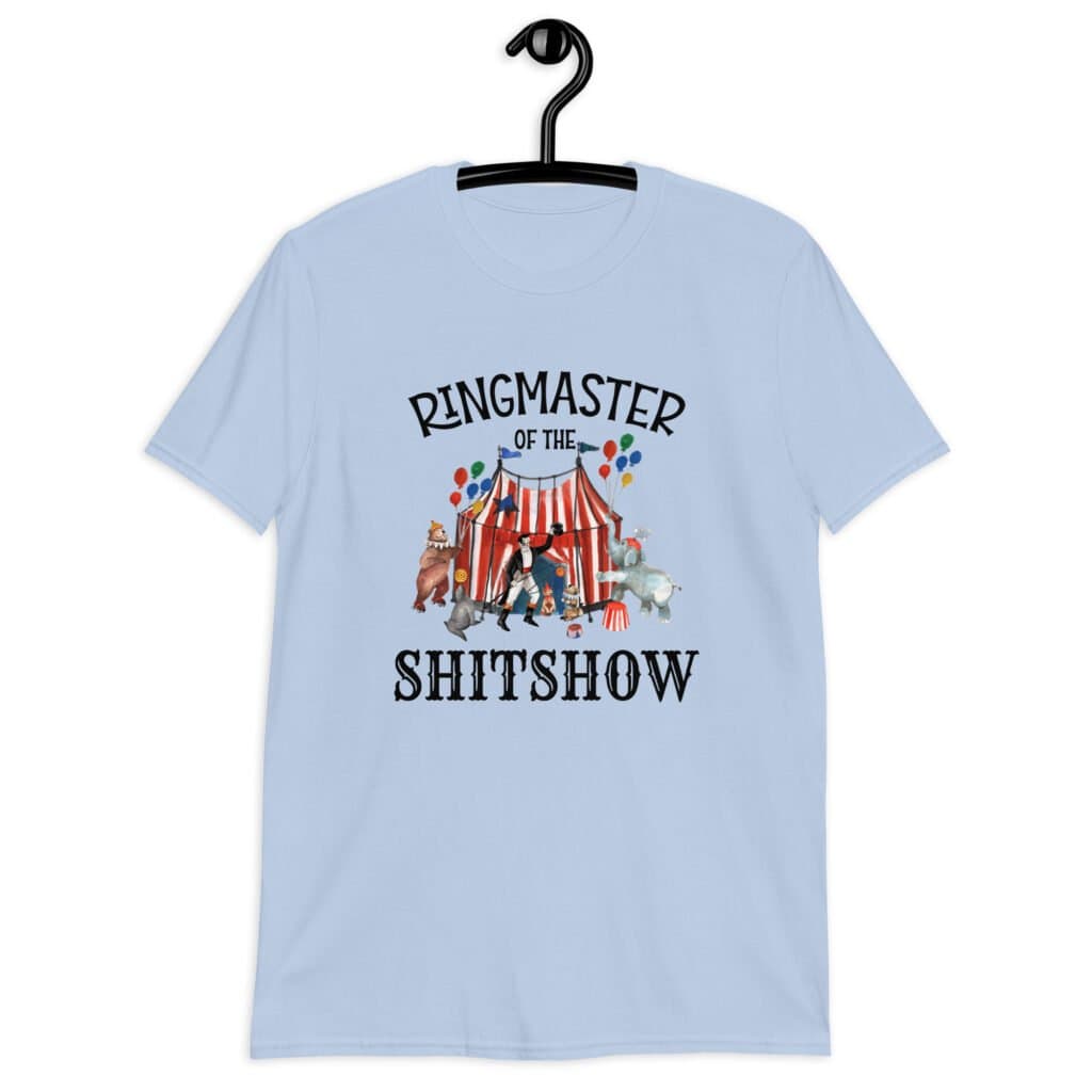 Light blue t-shirt with a circus theme graphic and the text 'Ringmaster of the Shitshow' printed on the front.