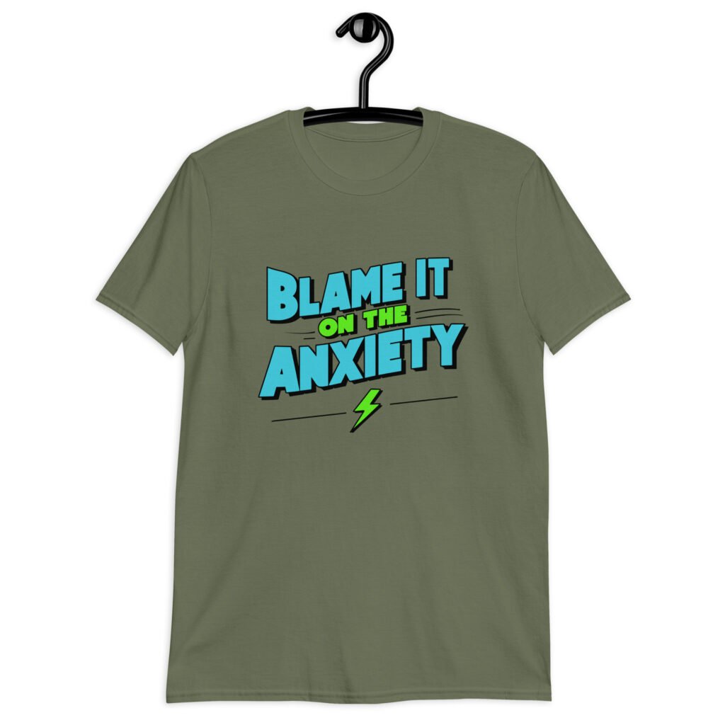 Military green t-shirt with the phrase 'Blame is on the anxiety' printed on the front. The graphics are bold and in aqua and lime green.