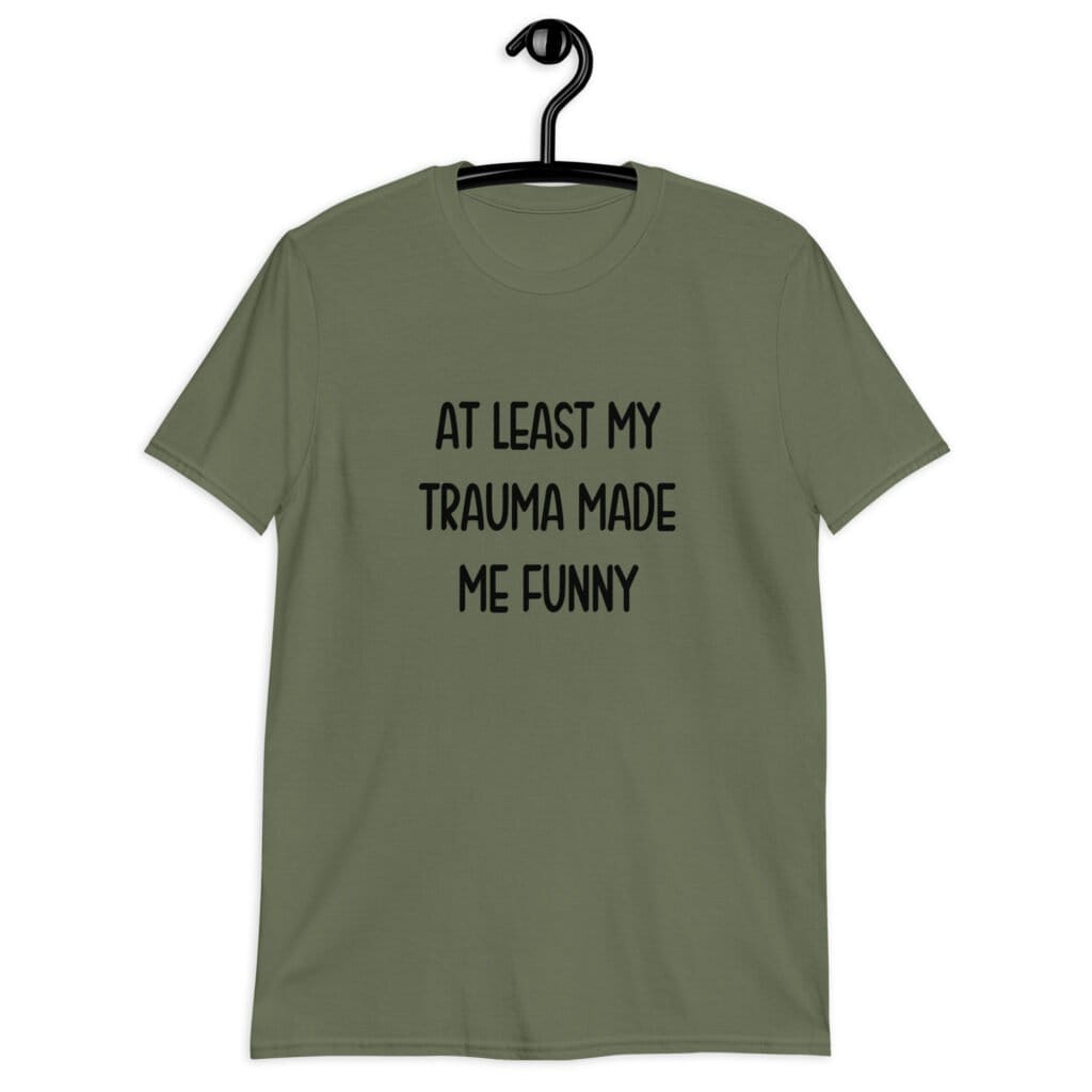 Military green t-shirt with the text 'At least my trauma made me funny' printed on the front.