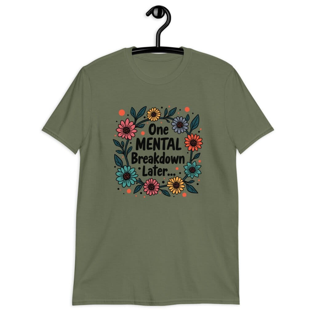 Military green t-shirt with a multi color floral wreath design printed on the front. The words 'One mental breakdown later...' are printed in the center of the wreath.