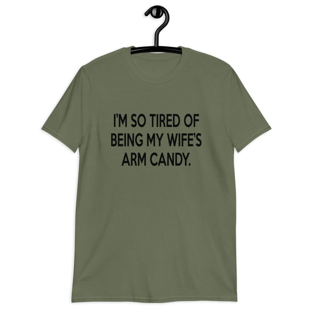 Military green t-shirt with the funny phrase 'I'm so tired of being my wife's arm candy' printed on the front.