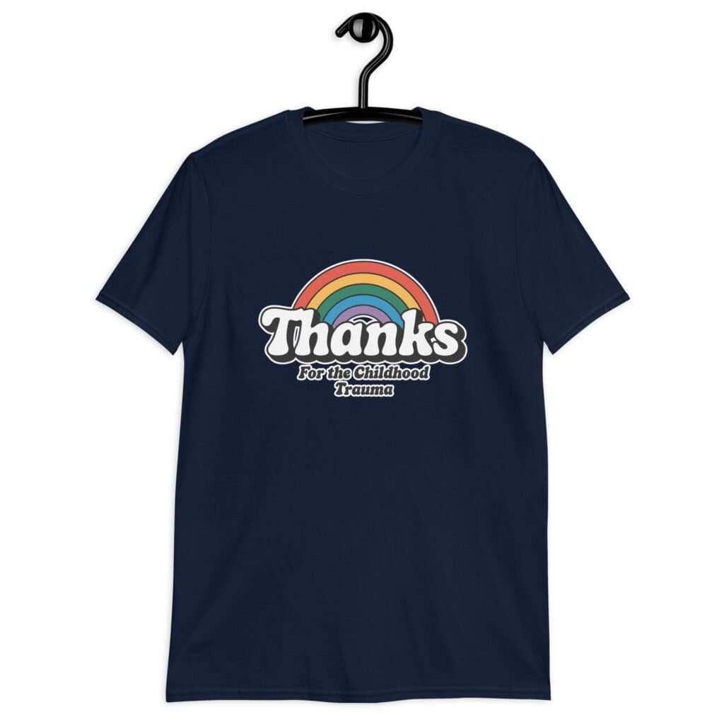 Navy blue t-shirt with an image of a rainbow and the words 'Thanks for the childhood trauma' printed on the front. The word Thanks is large and the rest of the words are smaller under.