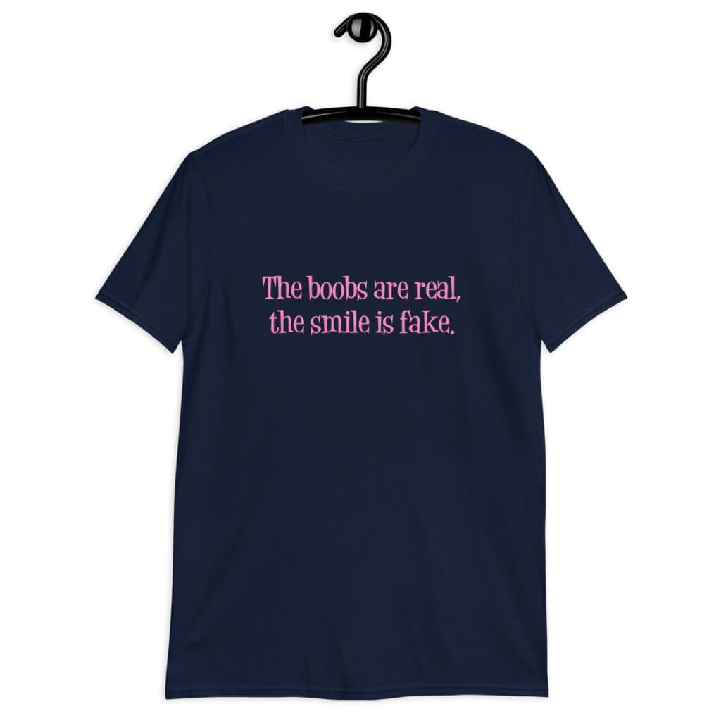 Navy blue t-shirt with the text 'The boobs are real, the smile is fake.' printed in pink on the front.