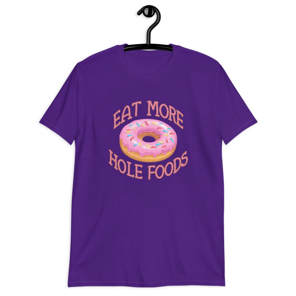 Purple t-shirt that has an image of a donut with pink icing and sprinkles and the text 'Eat more hole foods' printed on the front.