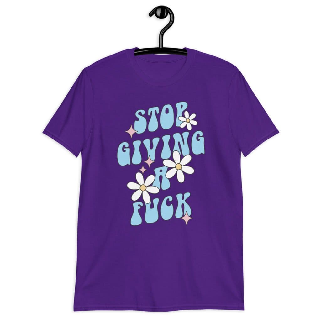 Purple t-shirt with a retro daisy and star design and the text 'Stop giving a fuck' printed on the front.