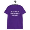Purple t-shirt with the funny phrase 'I'm so tired of being my wife's arm candy' printed on the front.