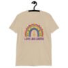 Sand color t-shirt with an image of a boho style rainbow. There is an upside down cross in the center arch of the rainbow and the text 'Love like Lucifer' printed under. The graphics are printed on the front.