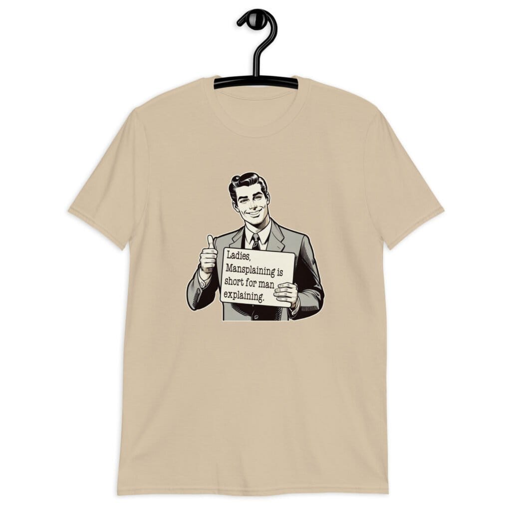 Sand color t-shirt with graphic of a retro man holding sign that says 'Ladies, mansplaining is short for man explaining' printed on the front.