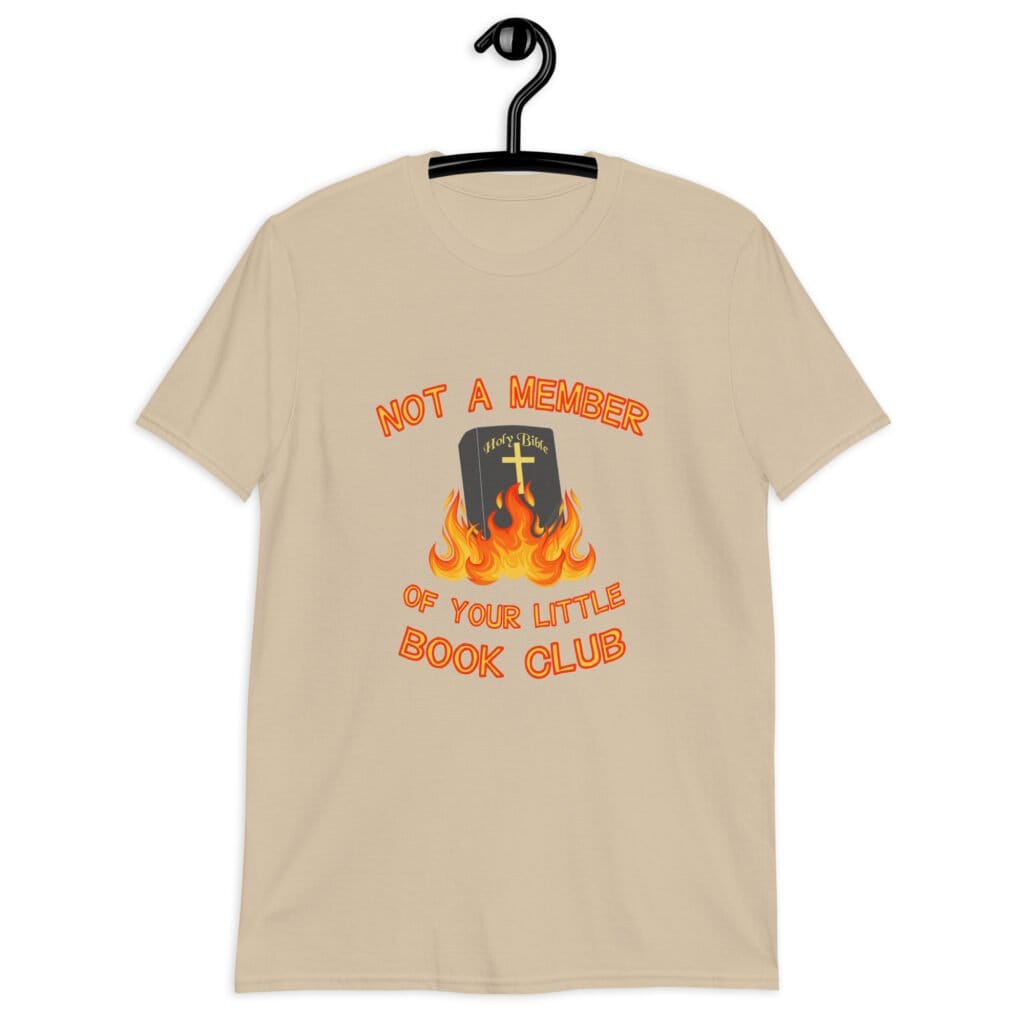 Sand color t-shirt with image of a burning bible and the text 'Not a member of your little book club' printed on the front.