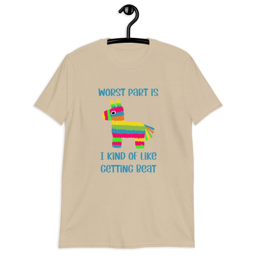Sand color t-shirt with an image of a colorful donkey pinata with the words 'Worst part is I kind of like getting beat' printed on the front.