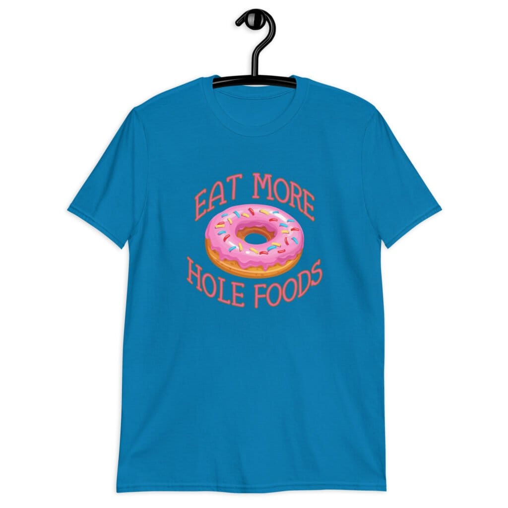 Sapphire blue t-shirt that has an image of a donut with pink icing and sprinkles and the text 'Eat more hole foods' printed on the front.