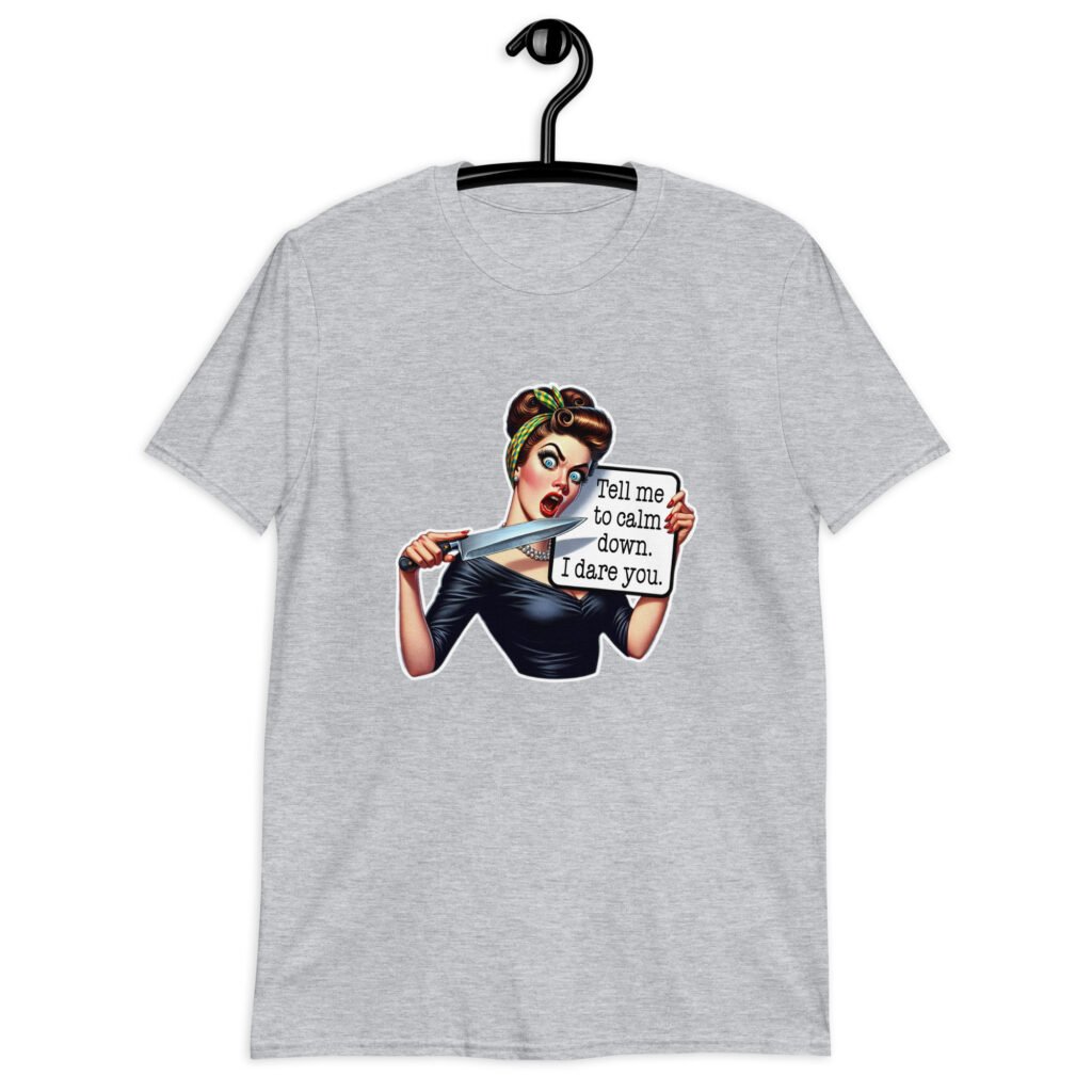 Sport grey t-shirt that has a graphic of an angry looking retro woman holding a knife and a sign. The sign says 'Tell me to calm down. I dare you.' The graphic is printed on the front of the shirt.