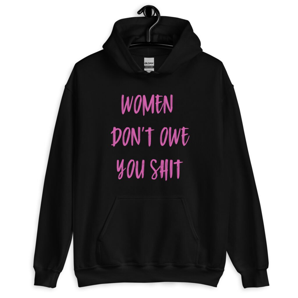 Black hoodie sweatshirt with the words 'Women don't owe you shit' printed on the front in pink.