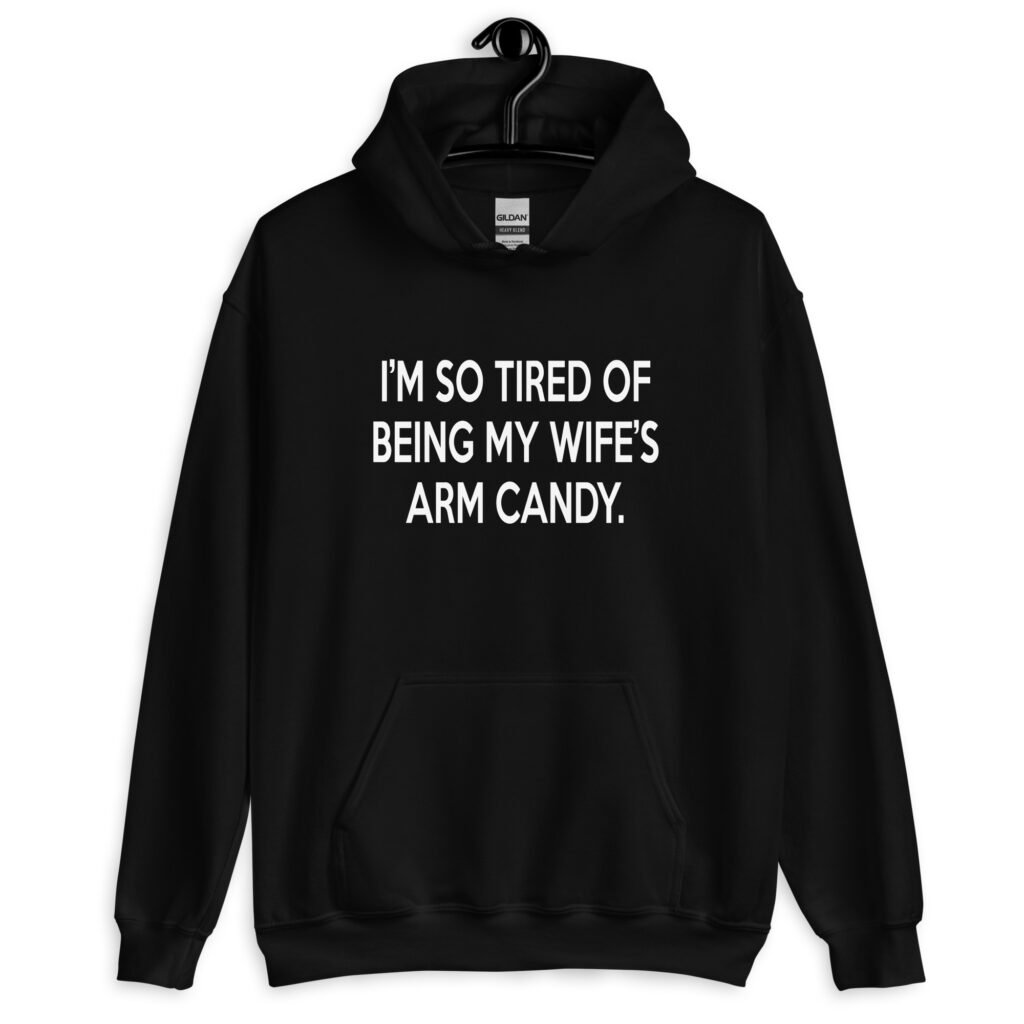 Black hoodie sweatshirt with the funny phrase 'I'm so tired of being my wife's arm candy' printed on the front.