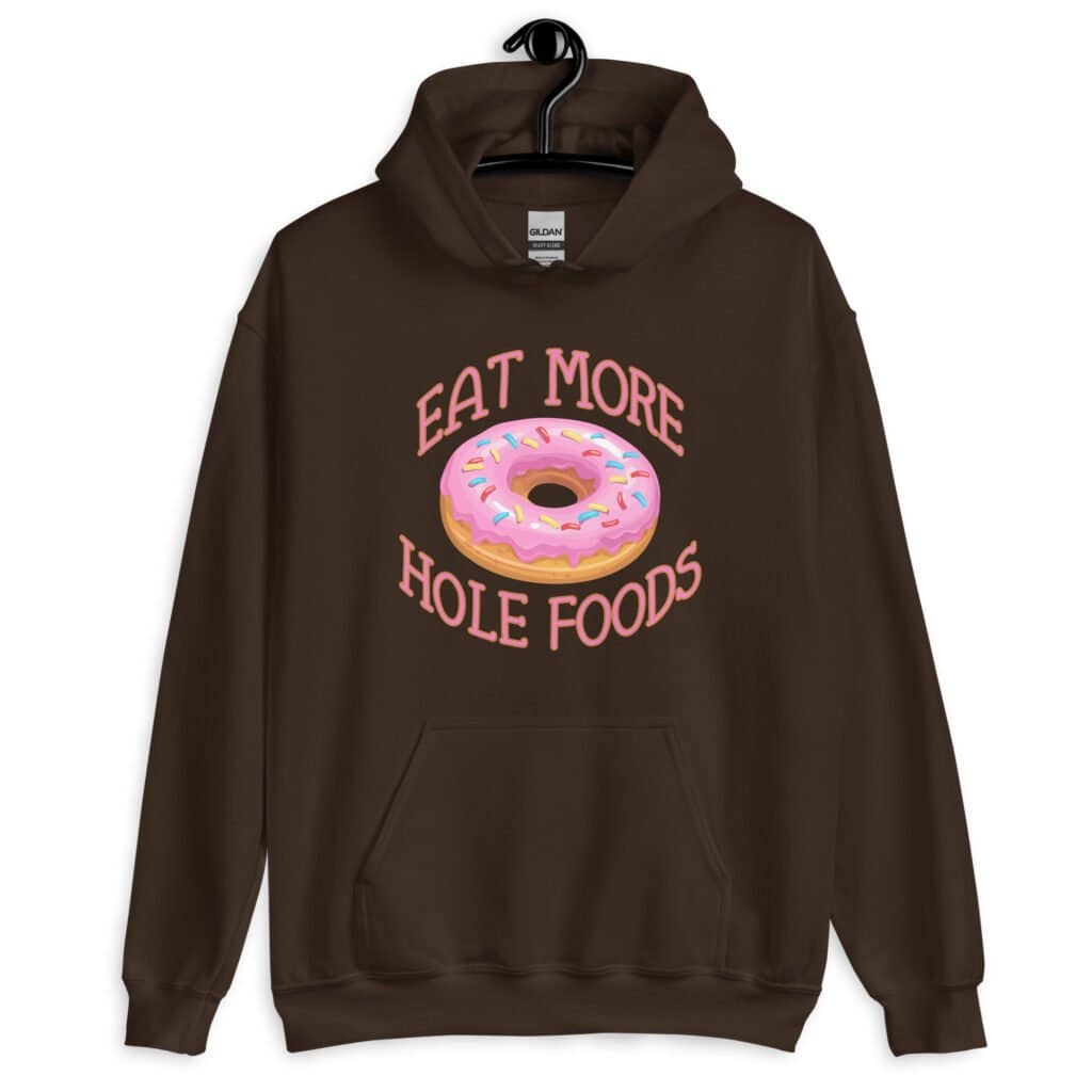 Dark chocolate brown hoodie sweatshirt with an image of a donut with pink icing and sprinkles and the text 'Eat more hole foods' printed on the front.