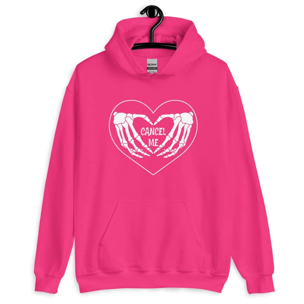 Heliconia pink hoodie sweatshirt with a heart and skeleton hands making a heart shape printed on the front. The words 'Cancel Me' are inside of the heart.