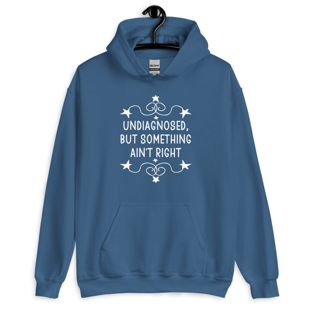 Indigo blue hoodie sweatshirt with the phrase 'Undiagnosed, but something ain't right 'printed on the front. The text is white and has a star graphic embellishment around the words.