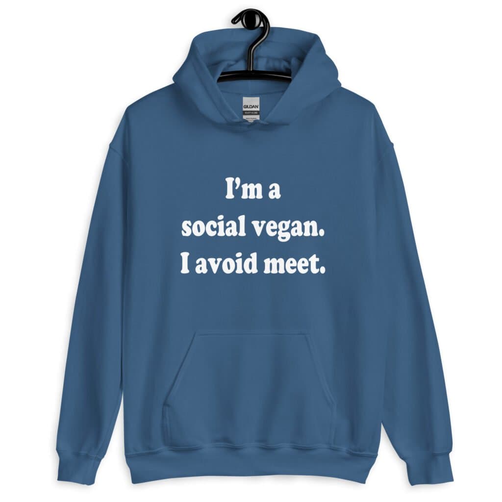 Indigo blue hoodie sweatshirt with the pun phrase 'I'm a social vegan. I avoid meet.' printed on the front.