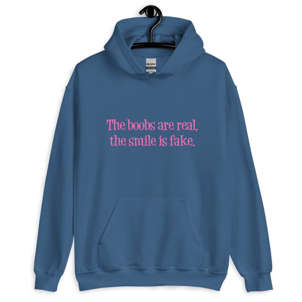 Indigo blue hoodie sweatshirt with the text 'The boobs are real, the smile is fake.' printed in pink on the front.