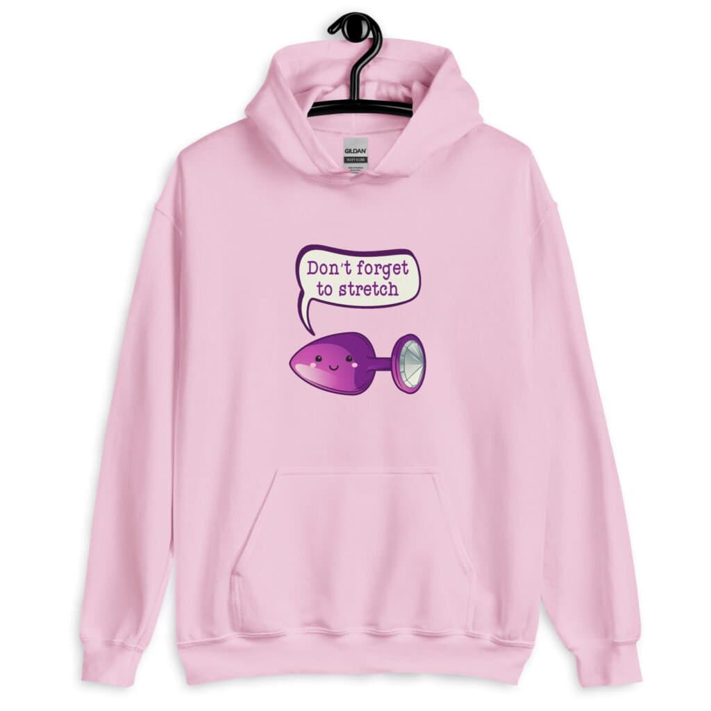 Light pink hoodie sweatshirt that has image of a purple anal plug with a smile face with a speech bubble above with the words 'Don't forget to stretch'. The graphics are printed on the front of the hoodie.