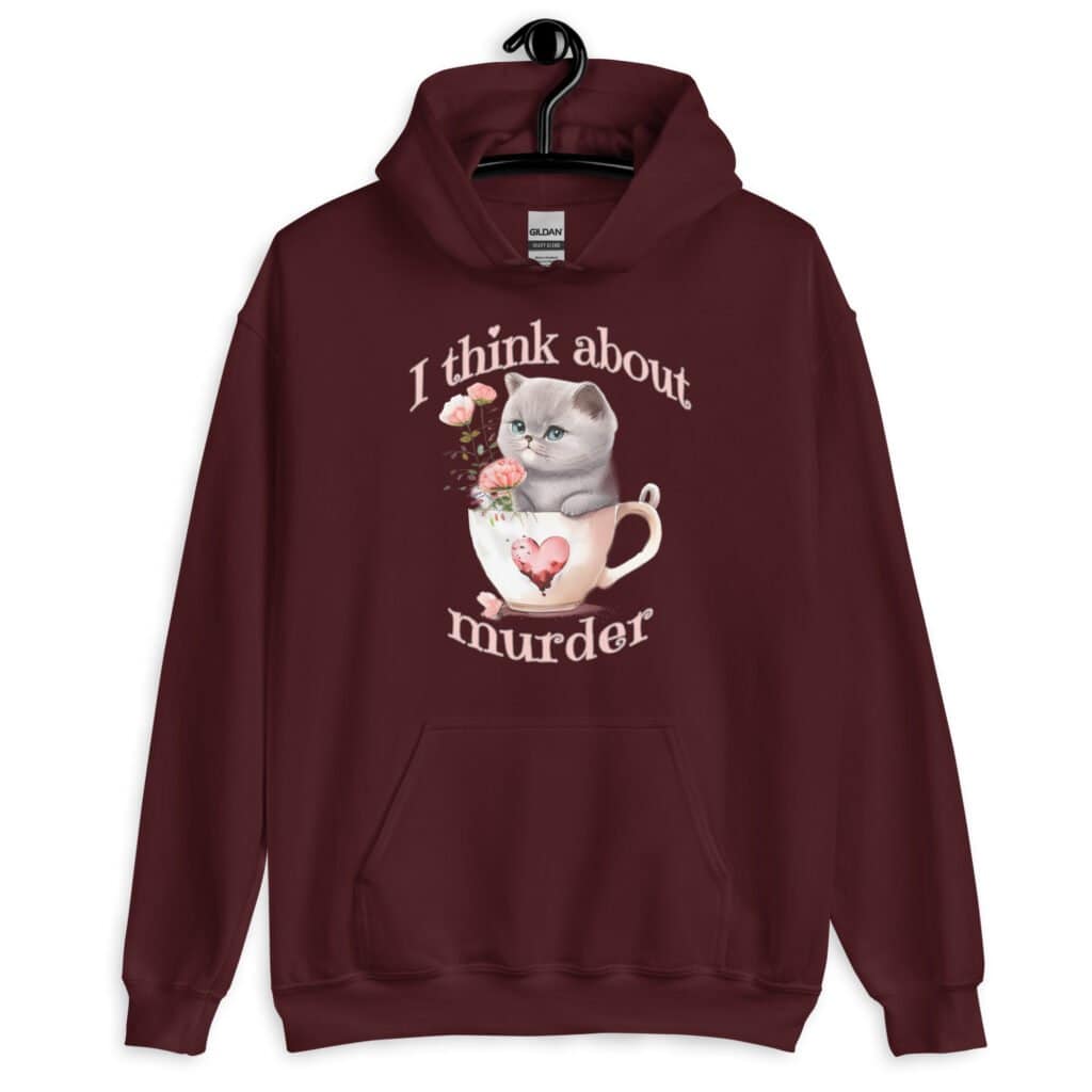 Maroon hoodie sweatshirt that says 'I think about murder' with image of cute fluffy kitten sitting in a teacup printed on the front.