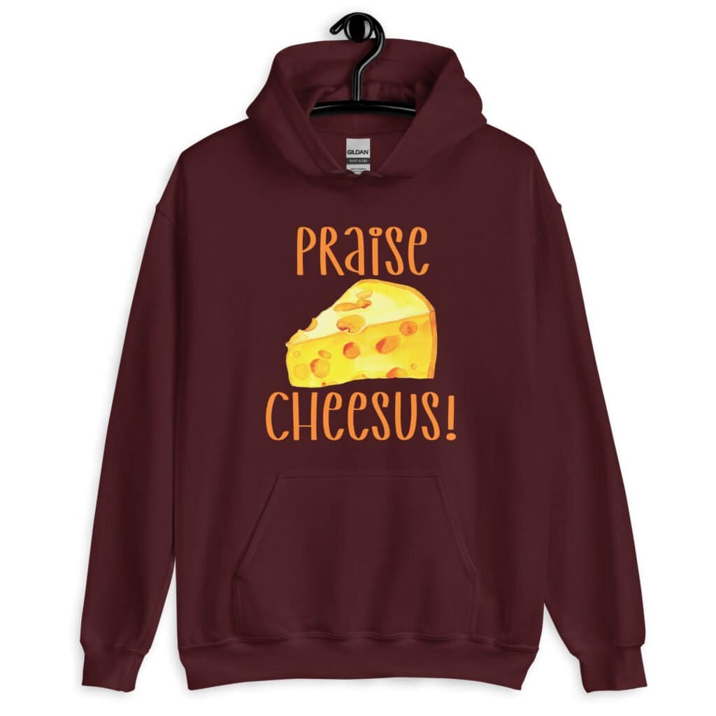 Maroon hoodie sweatshirt with funny graphics of a piece of swiss cheese and the text 'Praise Cheesus' printed on the front of the shirt in yellow and orange.
