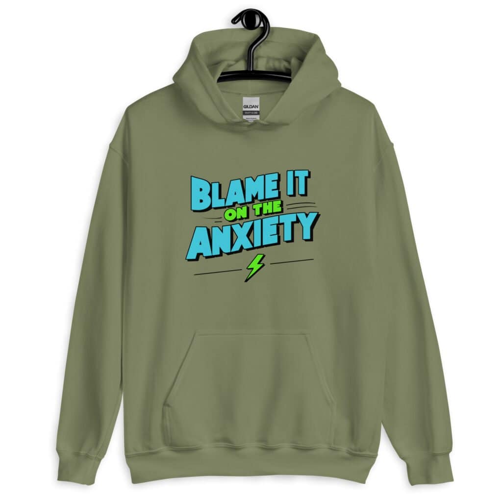 Military green hoodie sweatshirt with the phrase 'Blame is on the anxiety' printed on the front. The graphics are bold and in aqua and lime green.