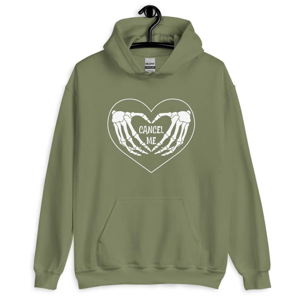 Military green hoodie sweatshirt with a heart and skeleton hands making a heart shape printed on the front. The words 'Cancel Me' are inside of the heart.