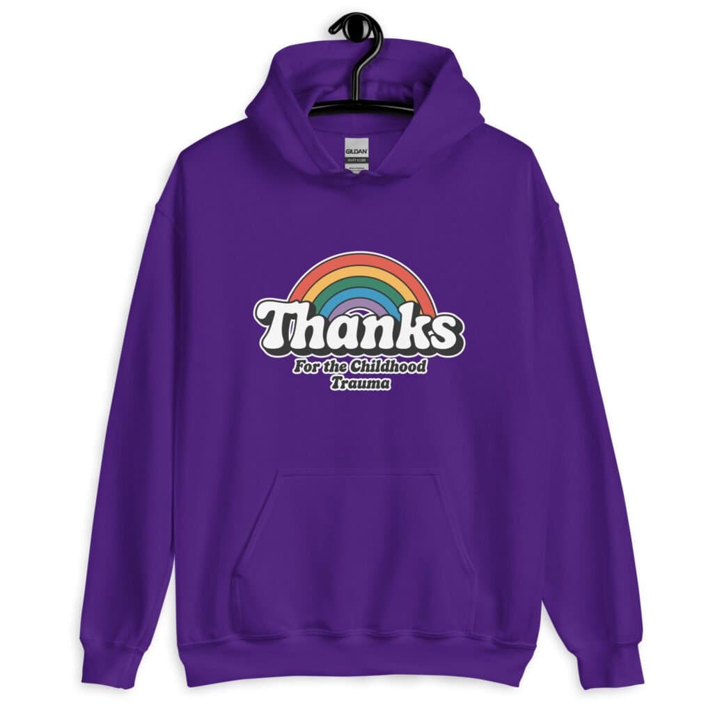 Purple hoodie sweatshirt with an image of a rainbow and the words 'Thanks for the childhood trauma' printed on the front. The word Thanks is large and the rest of the words are smaller under.